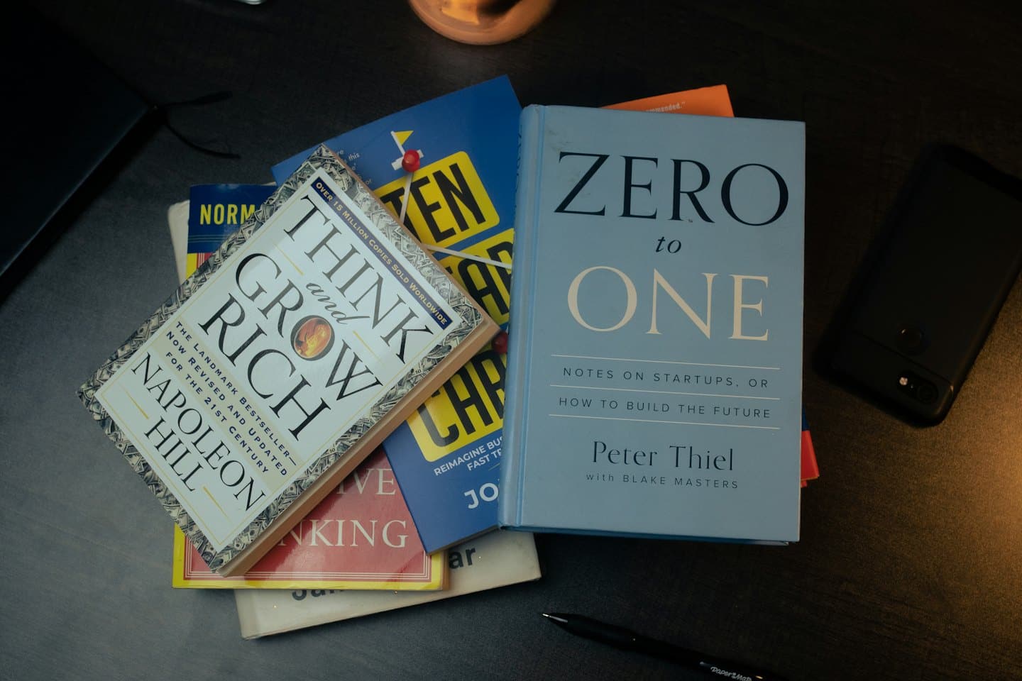 Business books, a smartphone, and a pen on a desk.